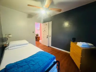 a bedroom with a bed and a ceiling fan at The Pink Paradise in Bronxdale