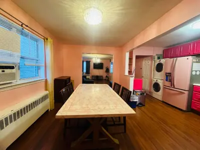 a dining room with a table and a kitchen at The Pink Paradise in Bronxdale