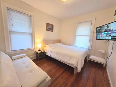 a bedroom with a bed and a flat screen tv at Entire Beautiful 1BR for You! [R] in Whitestone