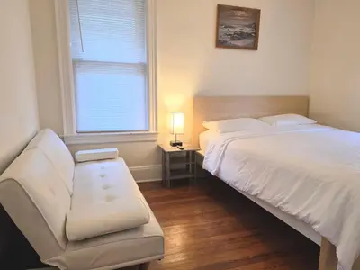 a bedroom with a bed and a couch and a window at Entire Beautiful 1BR for You! [R] in Whitestone