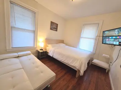 a bedroom with two beds and a flat screen tv at Entire Beautiful 1BR for You! [R] in Whitestone