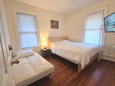 a bedroom with a bed and a couch and two windows at Entire Beautiful 1BR for You! [R] in Whitestone