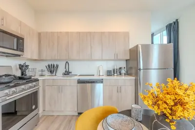 a kitchen with wooden cabinets and stainless steel appliances at Bright and Bold Escape with NYC Views and Free Parking, Sleeps 9 and 2 Baths in Newark