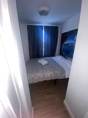 a small bedroom with a bed and blue curtains at Cozy Apartments Woodside near Manhattan in Queens