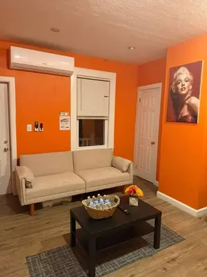 a living room with orange walls and a couch and a table at Cozy Apartments Woodside near Manhattan in Queens