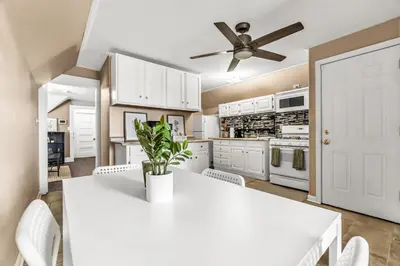 a kitchen with white cabinets and a white table and chairs at Bedroom walking distance to Yale Bridgeport Hospital in Bridgeport