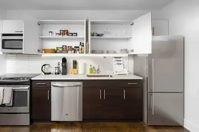 a kitchen with white cabinets and a stainless steel refrigerator at Large Upper East Side 1BD Elevator Rooftop in New York