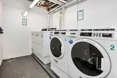 a laundry room with two washing machines and a clock at Large Upper East Side 1BD Elevator Rooftop in New York