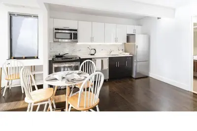 a kitchen with a table and chairs and a kitchen with white cabinets at Large Upper East Side 1BD Elevator Rooftop in New York