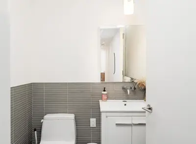 a bathroom with a toilet and a sink and a mirror at Luxury 2BD nr Wall St Gym Rooftop w/d in New York