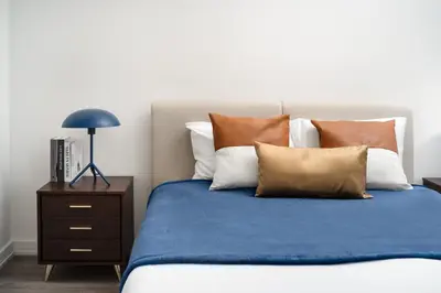 a bedroom with a bed with pillows and a nightstand at Luxury 2BD nr Wall St Gym Rooftop w/d in New York