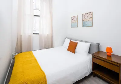 a bedroom with a white bed and a wooden nightstand at Spacious Luxury 2BD Downtown Gym W/D Doorman in New York