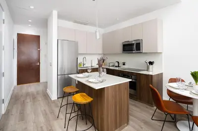 a kitchen with white cabinets and a table and chairs at Spacious Luxury 2BD Downtown Gym W/D Doorman in New York