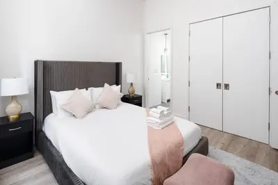 a bedroom with a white bed and a chair at Chic 1BD with Rooftop W/D in Unit Downtown in New York