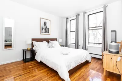 a white bedroom with a bed and two windows at 2Bed Bliss by Central Park North in New York