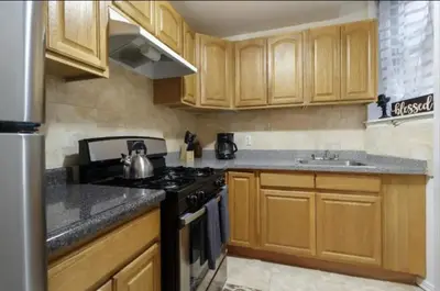 a kitchen with wooden cabinets and a stove top oven at 2Bed Bliss by Central Park North in New York