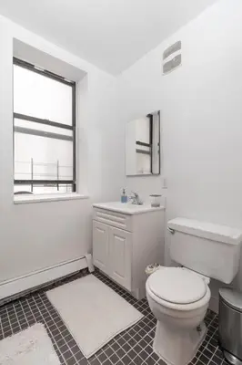a white bathroom with a toilet and a sink at 2Bed Bliss by Central Park North in New York