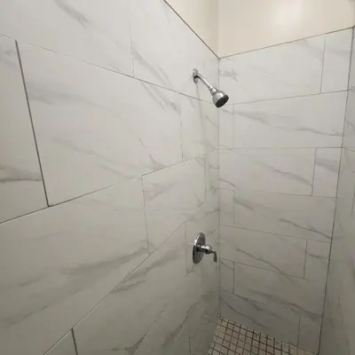 a bathroom with a shower with white marble tiles at New York City Guest House 2 in New York