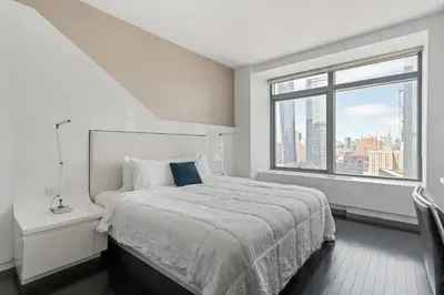 a white bedroom with a bed and a large window at Financial District 1br w WD gym elevator NYC-1376 in New York