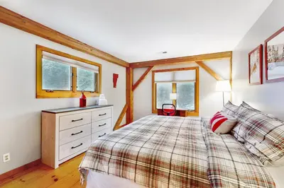 a bedroom with a bed and a dresser and two windows at Whistling Peak in Wilmington