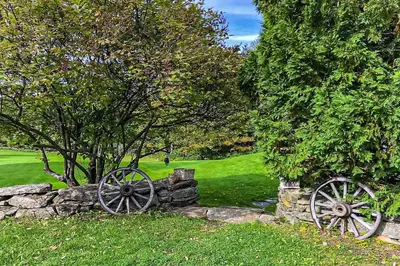 a stone wall with two woodenokedoked wheels in a field at Whistling Peak in Wilmington