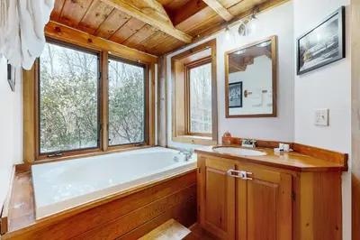 a bathroom with a tub and a sink and a window at Whistling Peak in Wilmington