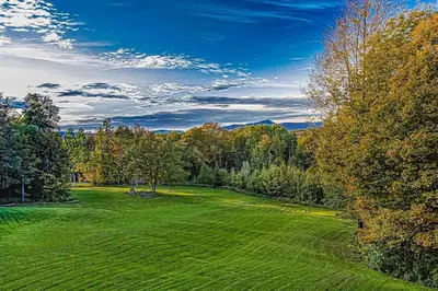 a large green field with trees in the background at Whistling Peak in Wilmington