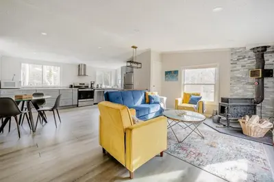 a living room with a yellow couch and a table at EV Serene Modern Cozy Waterfront Fireplace Cottage in Livingston Manor