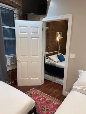 a small room with two beds and a door with a bedroom at Nest 1 bedroom Aparthotel with kitchenette in New York