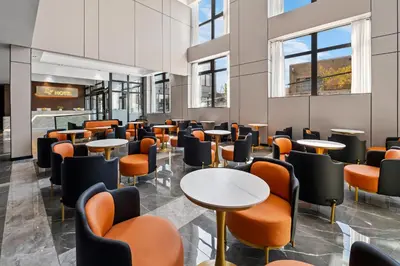 a waiting room with tables and chairs and windows at Ly New York Hotel in College Point