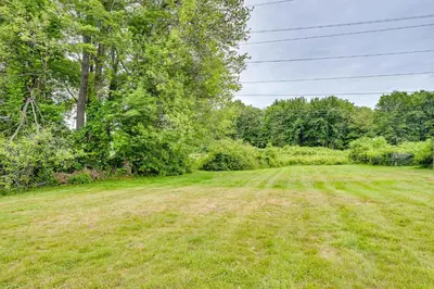 a field of grass with trees in the background at Vintage Windsor Home Private Yard and Covered Deck in Windsor