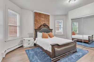 a bedroom with a bed and a brick wall at Frog Hollow Red Door Loft in Hartford