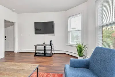 a living room with a blue couch and a tv at Frog Hollow Red Door Loft in Hartford