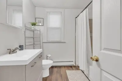 a white bathroom with a toilet and a sink at Frog Hollow Red Door Loft in Hartford
