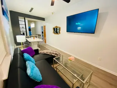 a living room with a black couch and a flat screen tv at NYC Oasis in Mott Haven