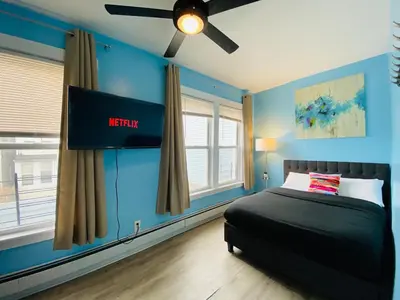 a bedroom with blue walls and a bed with a television at NYC Oasis in Mott Haven