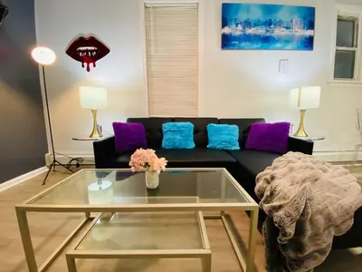 a living room with a black couch and purple pillows at NYC Oasis in Mott Haven