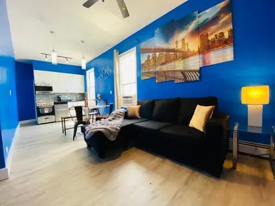 a living room with a black couch and a blue wall at NYC Oasis in Mott Haven