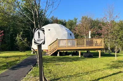 a sign in front of a round house with a deck at Unique Escapes - 007 Geodome in Monticello