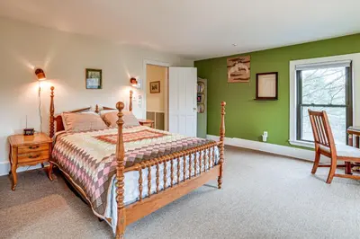 a bedroom with a bed and a table and a chair at Fly Creek Historic Home By Cooperstown! in Fly Creek