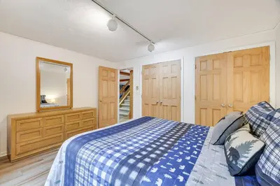 a bedroom with a blue and white bed and wooden cabinets at Lake Front, Hot Tub, Fire Pit, FP, Boats, Ski in Gouldsboro
