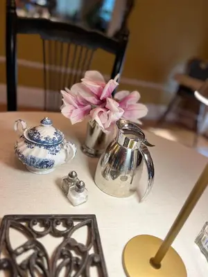 a table with a tea kettle and a vase with flowers at Antique1242 British Bed & Breakfast in Enfield