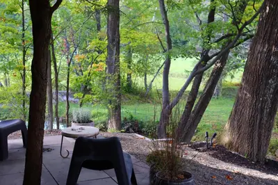 a patio with a table and chairs and trees at WOODSTOCK HISTORIC ARTIST ESTATE - THE MUSEUM HOUSE in Woodstock