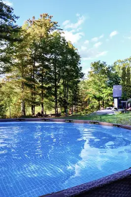 a large blue swimming pool with trees in the background at WOODSTOCK HISTORIC ARTIST ESTATE - THE MUSEUM HOUSE in Woodstock
