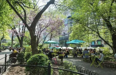 a group of people sitting at tables in a park at Chic One Bedroom Retreat in Downtown Manhattan in New York