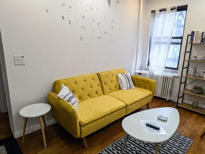 a living room with a yellow couch and a table at Chic One Bedroom Retreat in Downtown Manhattan in New York