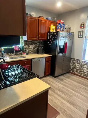 a kitchen with a stainless steel refrigerator and wooden cabinets at Genevieve’s comfort pad in Jersey City