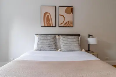 a bedroom with a white bed with two pictures on the wall at Lenox Hill 2br w elevator doorman nr art NYC-1389 in New York