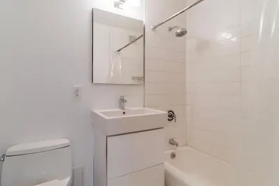 a white bathroom with a sink and a toilet and a tub at Lenox Hill 2br w elevator doorman nr art NYC-1389 in New York