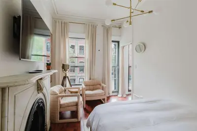 a white bedroom with a bed and a fireplace at The West Village Gem in New York